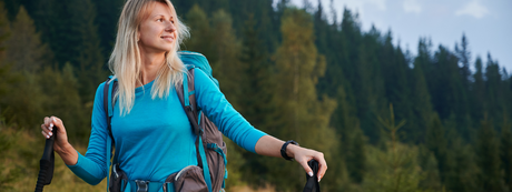 Signora che cammina in montagna facendo Nordic Walking